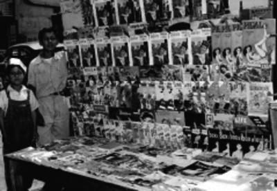 Adolescente y niña jnto a un expendio de periodicos y revistas