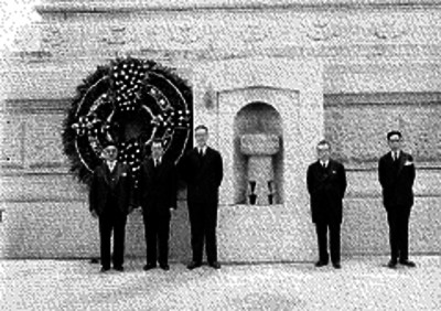 Funcionarios de la secretaría de hacienda montan guardia de honor, al pie del monumento de la independencia junto de un nicho con escultura de motivo prehispánico, retrato