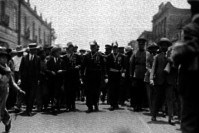 Veteranos caminando con multitud en una calle de la ciudad de México