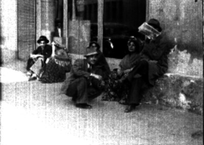 Gitanos sentados junto a unos caballeros fuera de alguna oficina
