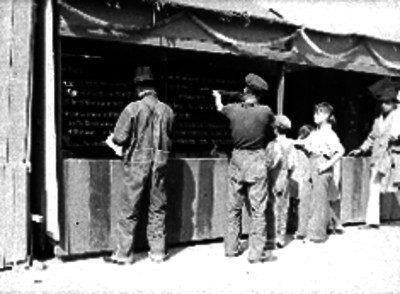 Hombres y niños jugando tiro al blanco en un stand de una feria