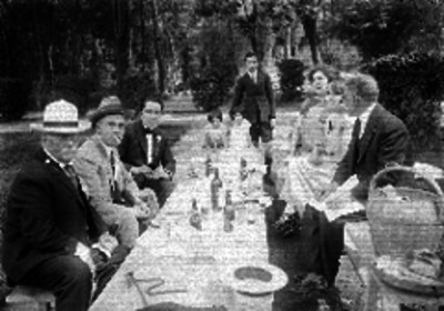 Hombres y mujeres platicando después de la comida en un día de campo