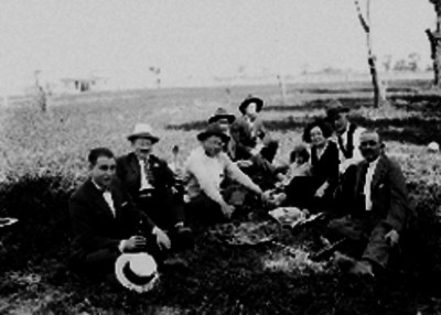 Hombres comiendo con una mujer y una niña en el campo, retrato