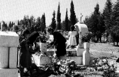 Grupo de personas depositando flores en tumbas el Día de muertos