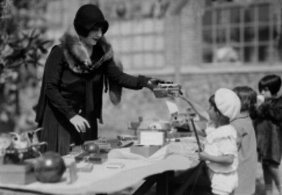 Mujer vestida elegantemente entregando un carro de juguete a un niño