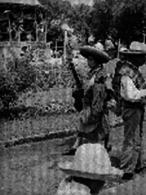 Mujer caminando con una guitarra en la mano y unos sombreros