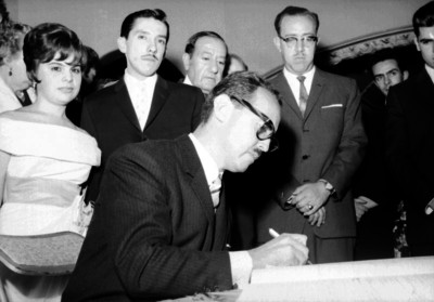 Hombre firma el libro de registro durante la boda de Enrique Alfaro y Virgen Llarena