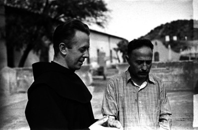 Fraile franciscano platica con un hombre en la calle