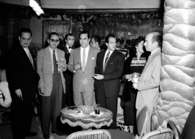 Carlos Amador y otras personas conversan en un salón durante evento social