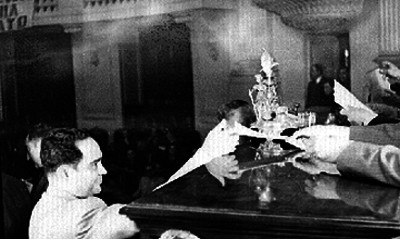 Legislador recibiendo documento durante sesión en la Cámara de Diputados