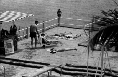 Turistas en una terraza playera, junto a una alberca