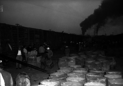 Hombres cargando barriles de pulque en una estación de ferrocarril