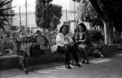 Mujeres sentadas conversan en una banca de la plaza Constitución