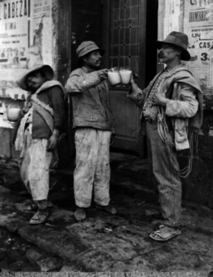 Cargadores brindando con pulque en una calle de la ciudad de México