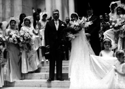 Pareja de novios acompañados de familiares y amigos en las escaleras frente a una iglesia, retrato de grupo