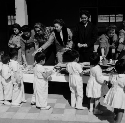 Mujeres elegantes entregando juguetes a niños y niñas durante el festival del día del niño
