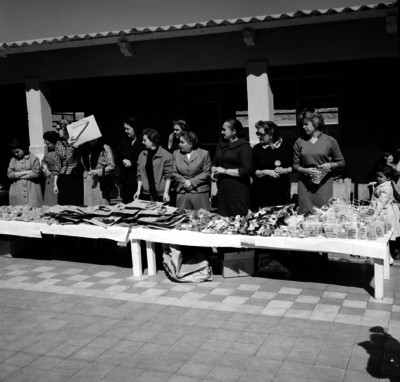 Niño caminando hacia unas mujeres con regalos durante la celebración del día del niño en una escuela