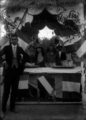 Mujeres con trajes regionales acompañadas de un hombre en un puesto durante una kermesse, retrato de grupo