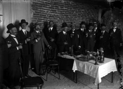 Miembros de la colonia española durante un brindis en el interior de una habitación, retrato de grupo