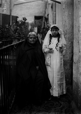 Niño de primera comunión acompañado poruna mujer en un pasillo, retrato