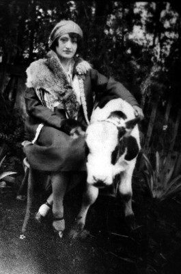 Mujer elegante abrazando a una vaquilla en un jardín, retrato