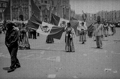 Mujeres vestidas con trajes típicos y banderas en un desfile del 1° de mayo en el zócalo