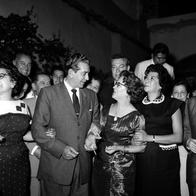Adolfo López Mateos acompañado de funcionarios y mujeres en una habitación