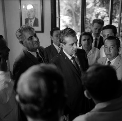 Adolfo López Mateos, rodeado de políticos y funcionarios en una habitación