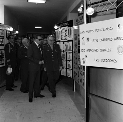 Adolfo López Mateos conversando con militar en una sala de exposiciones