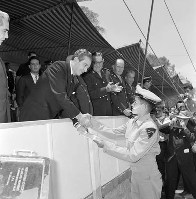 Adolfo López Mateos entregando una charola a un militar participante en el concurso ecuestres del cuerpo militar en un campo