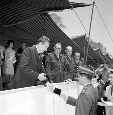 Adolfo López Mateos premiando a militar participante en un concurso ecuestre en un campo