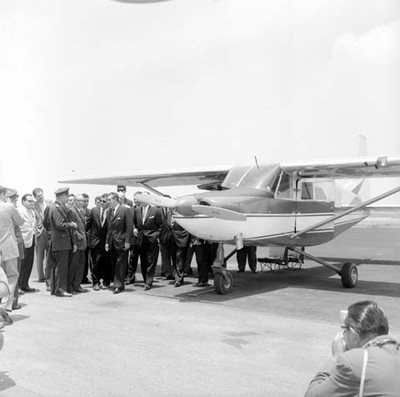 Adolfo López Mateos acompañado por miembros de su comitiva y empresarios conversando con un militar, durante la inspección de aviones hechos en San Luis Potosí