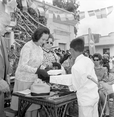 Eva Samano de López Mateos entregando obsequios a estudiante en una ceremonia