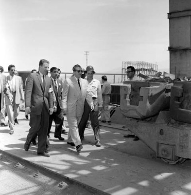 Adolfo López Mateos con otras personas recorriendo las instalaciones de una planta industrial, durante su campaña política por Monclova