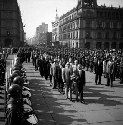 Funcionarios públicos pasando por una valla de soldados, durante la ceremonia a la bandera en el Zócalo