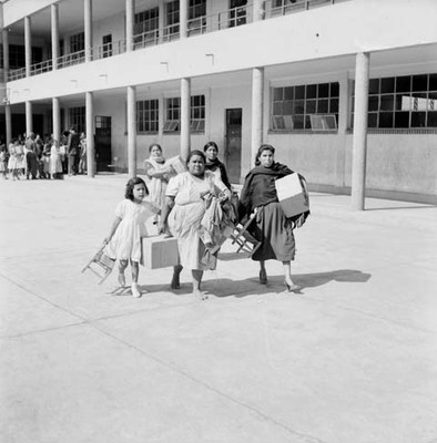 Mujeres pobres con despensas en un patio de escuela