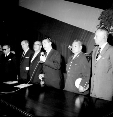Adolfo López Mateos pronunciando un discurso en compañía de David Franco Rodríguez y otras personalidades en una ceremonia