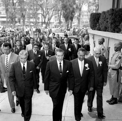 Adolfo López Mateos, Salomón Gónzalez Blanco y demás personalidades caminando frente a una guardia de soldados