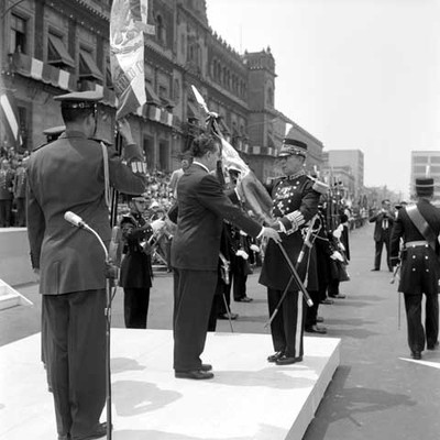 Adolfo López Mateos recibiendo el Lábaro Patrio de miembros del Estado Mayor Presidencial, durante la ceremonia de Jura de Bandera de conscriptos