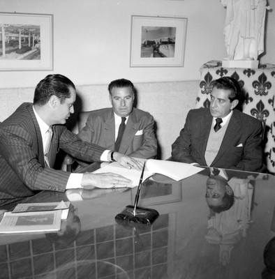 Adolfo López Mateos y empresarios conversando en una oficina durante su visita en campaña a la fábrica de hilados y tejidos San Luis S.A., en Tulancingo
