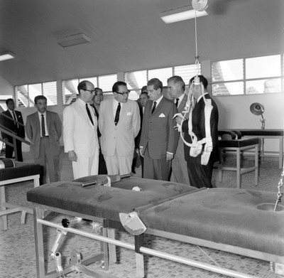 Adolfo López Mateos y otras personalidades observando una cama de rehabilitación de un hospital
