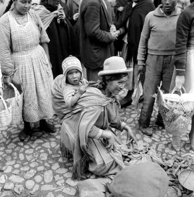 Vendedora quechua cargando a una niña sobre la espalda en una calle de La Paz, Bolivia