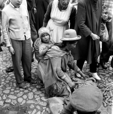 Mujer quechua con niña sobre la espalda vendiendo hierbas en una calle de La Paz, Bolivia