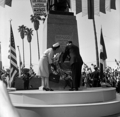 Adolfo López Mateos y Eva Sámano depositando una ofrenda en el monumento a Hidalgo, durante una ceremonia en Los Ángeles
