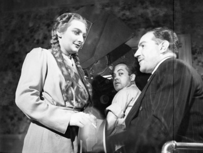 Actriz maquillada por mujer durante la filmación de una película en un estudio cinematográfico
