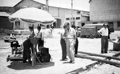 Director cinematográfico observa a un forillero revisar material para la filmación de una película