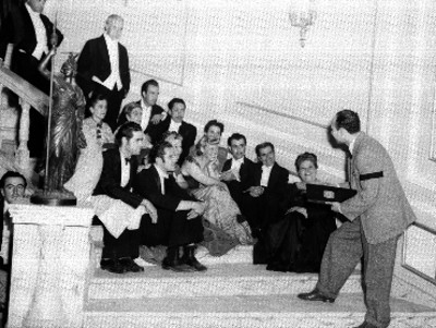 Actores y actrices sentados en una escalera escuchando instrucciones del director durante filmación de la película La Isla de la Pasión
