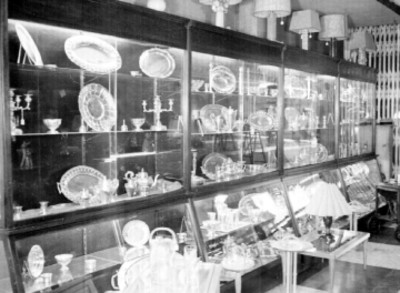 Charolas, lámparas y juegos de té en vitrinas de una tienda
