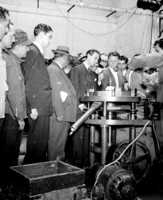 Ramón Beteta y funcionarios públicos observan el proceso de la fabricación de monedas