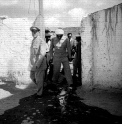 Funcionario público y militares recorriendo las caballerizas del cuartel de Santa Gertrudis
